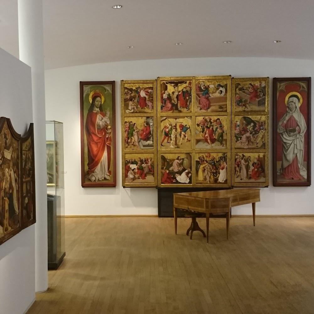 A museum gallery with paintings and a harpsichord.